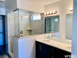 Bathroom featuring an enclosed shower, double vanity, and mirror
