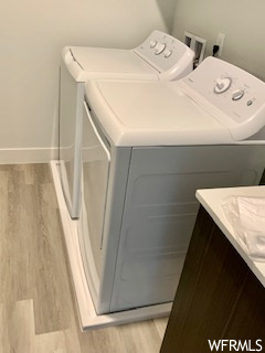 Clothes washing area featuring light hardwood flooring and washing machine and clothes dryer