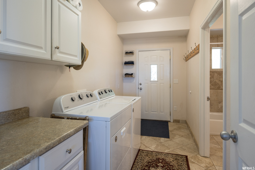 Laundry room with washing machine and clothes dryer, a healthy amount of sunlight, and light tile floors