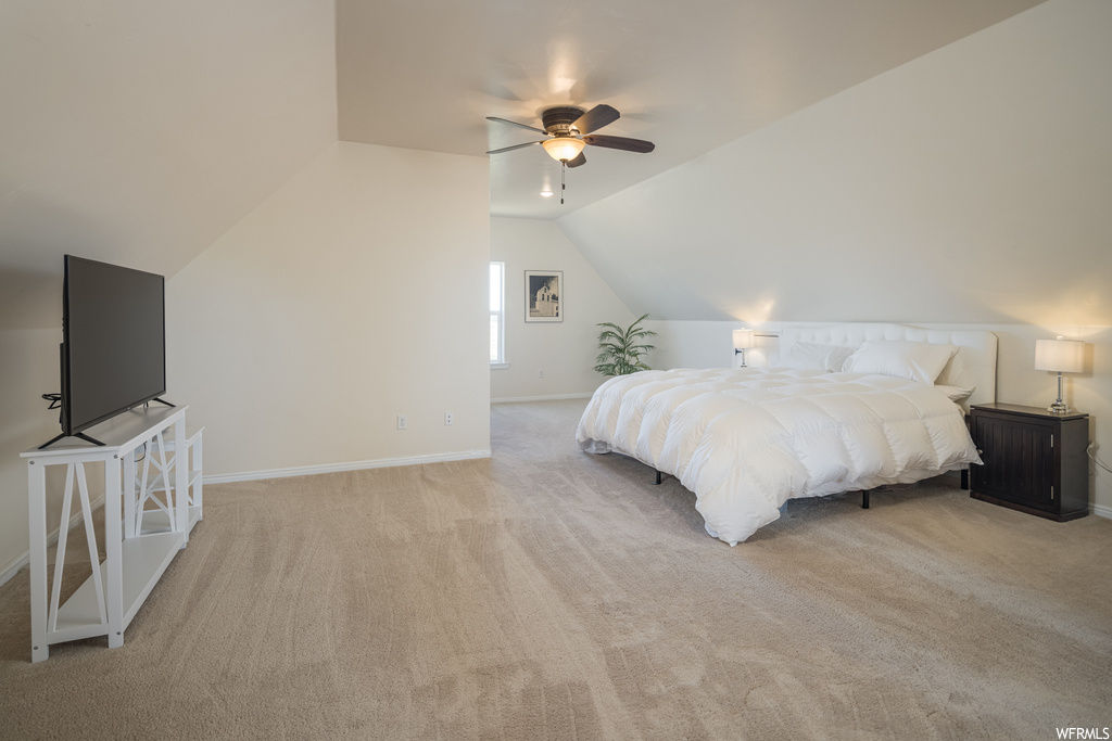Carpeted bedroom with vaulted ceiling and ceiling fan