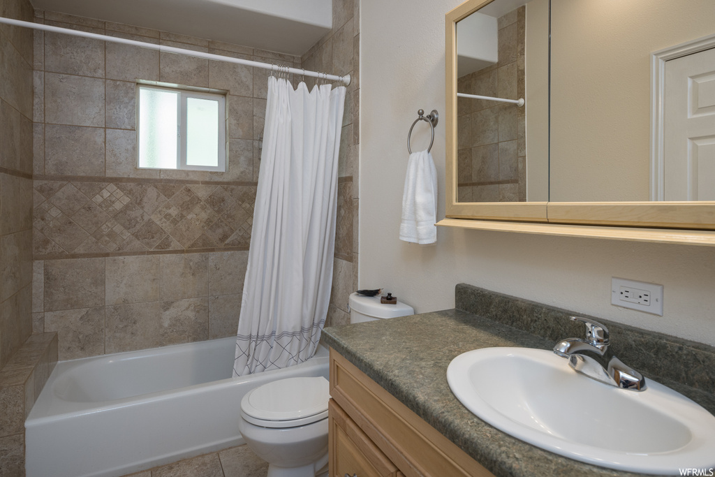 Full bathroom with tile floors, shower / tub combo with curtain, vanity, and mirror
