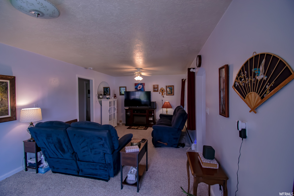 Living room featuring ceiling fan, carpet floors, and a textured ceiling