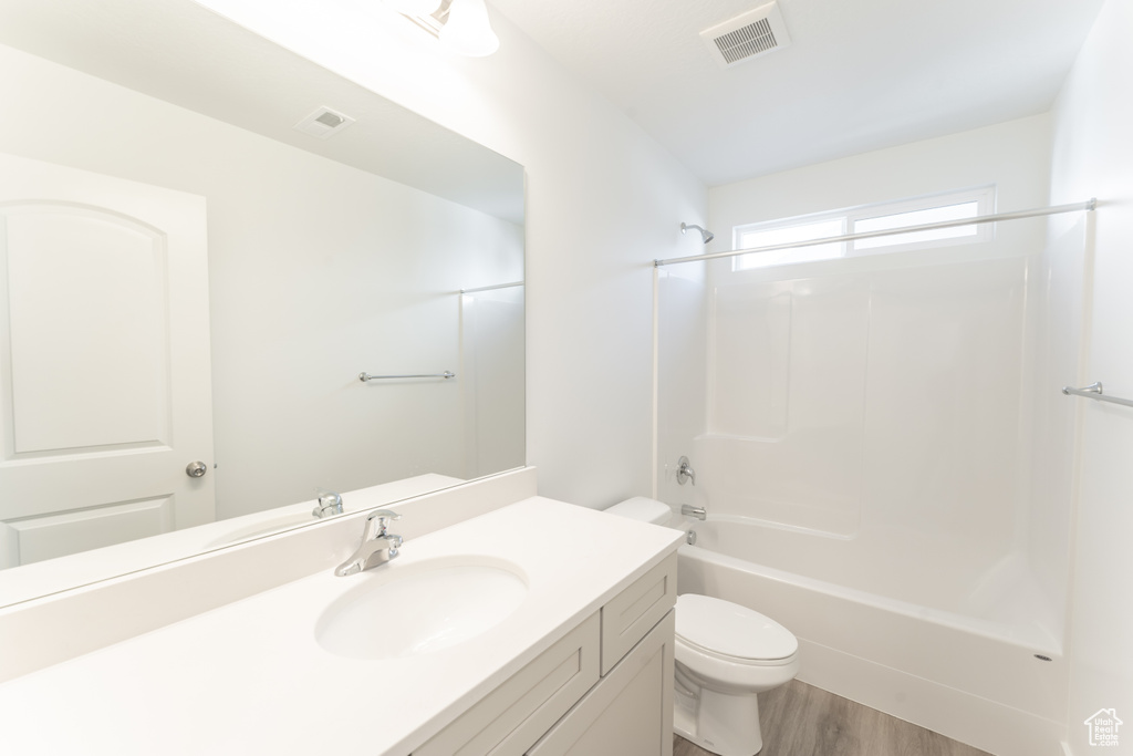 Full bathroom with bathing tub / shower combination, toilet, large vanity, and hardwood / wood-style flooring