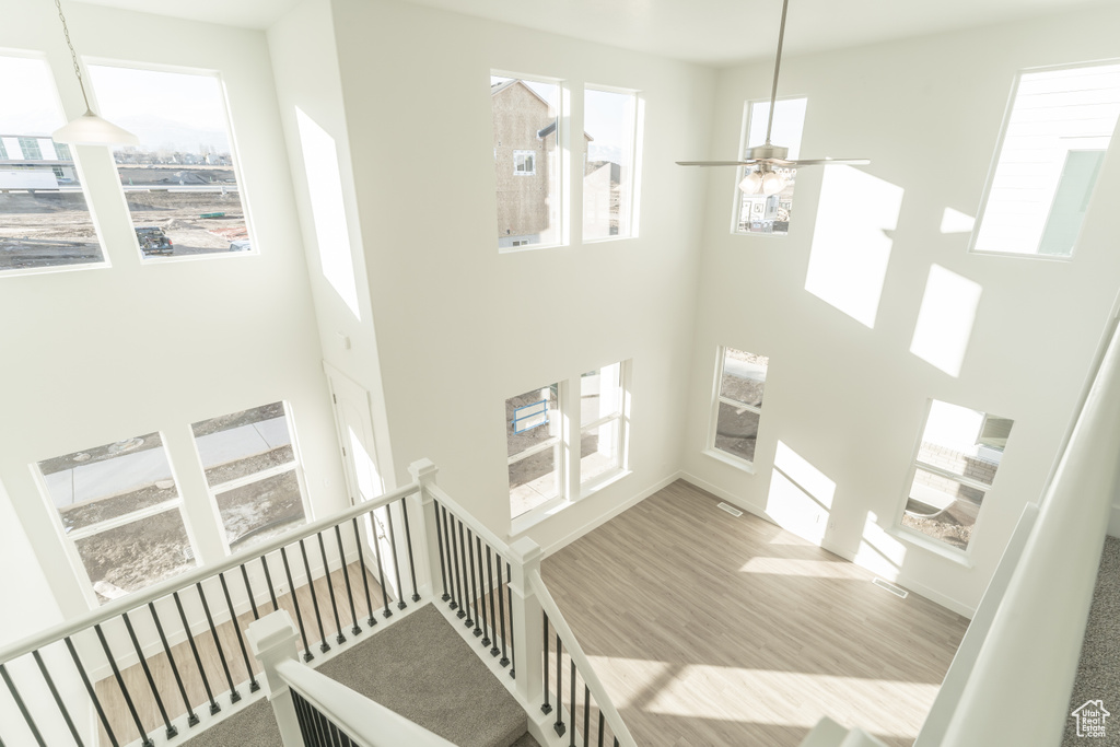 Stairs featuring light hardwood / wood-style flooring, a towering ceiling, and ceiling fan