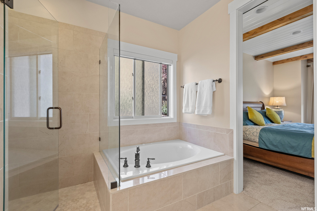 Bathroom featuring beam ceiling, shower with separate bathtub, and light tile floors