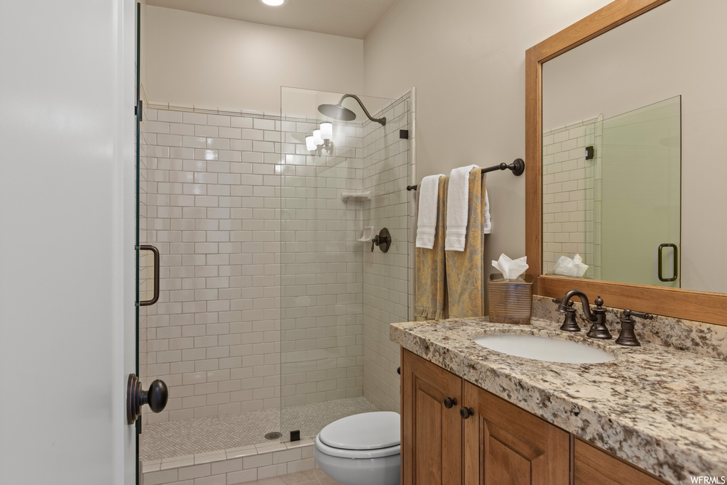 Bathroom with an enclosed shower, vanity with extensive cabinet space, light tile flooring, and mirror