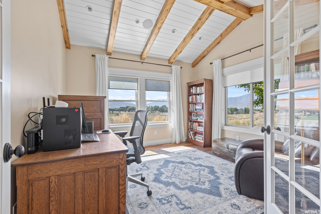 Office with lofted ceiling with beams, a wealth of natural light, and light hardwood floors