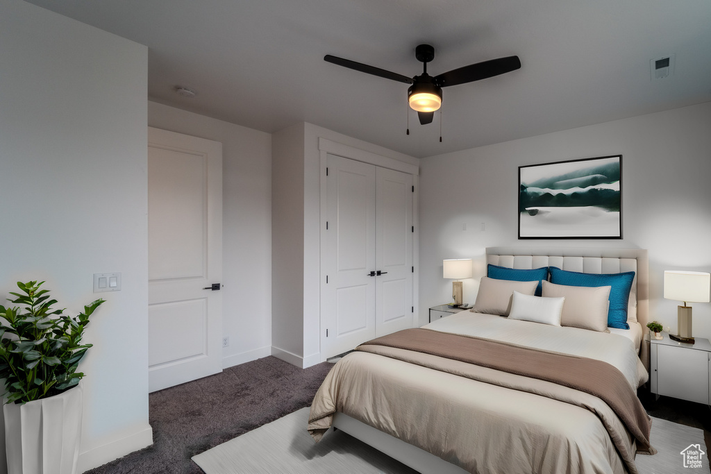 Bedroom with ceiling fan, dark carpet, and a closet