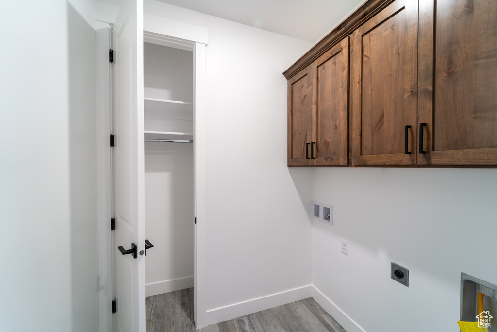 Laundry room featuring light hardwood / wood-style flooring, washer hookup, hookup for an electric dryer, and cabinets