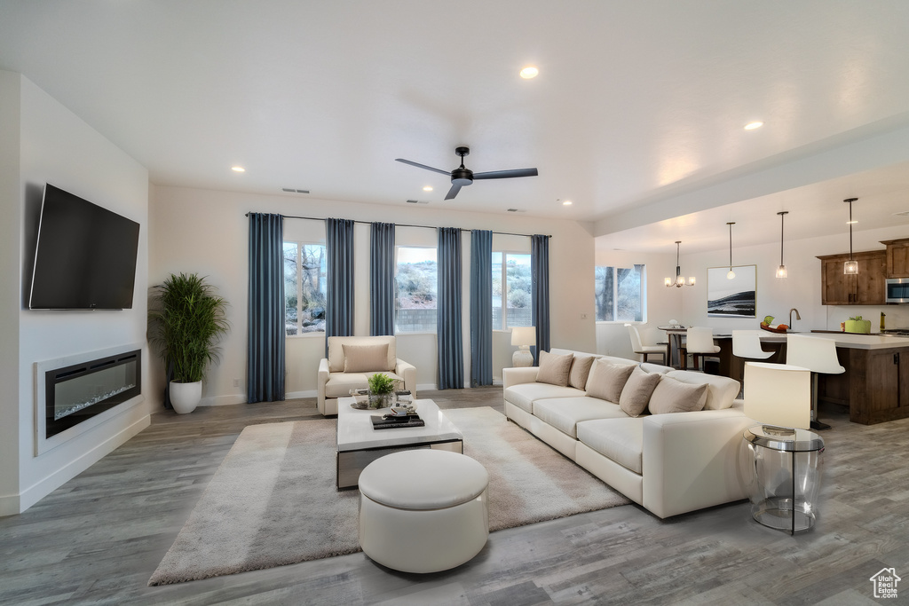 Living room featuring light wood-type flooring and ceiling fan with notable chandelier