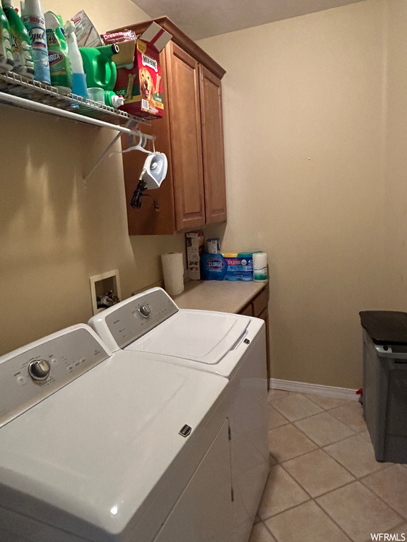 Washroom with washer and clothes dryer, light tile flooring, hookup for a washing machine, and cabinets