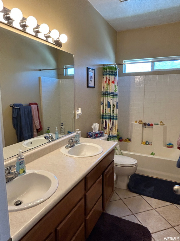 Full bathroom featuring dual sinks, toilet, shower / tub combo, and large vanity