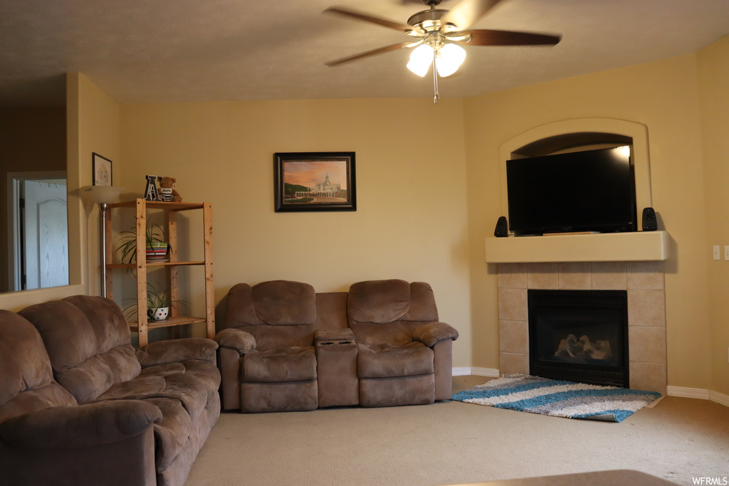 Carpeted living room with a fireplace and ceiling fan