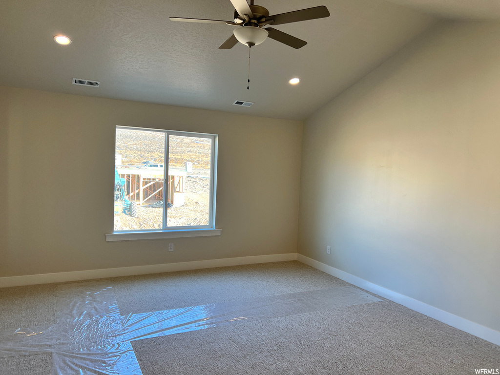 Spare room with ceiling fan, a textured ceiling, carpet, and vaulted ceiling