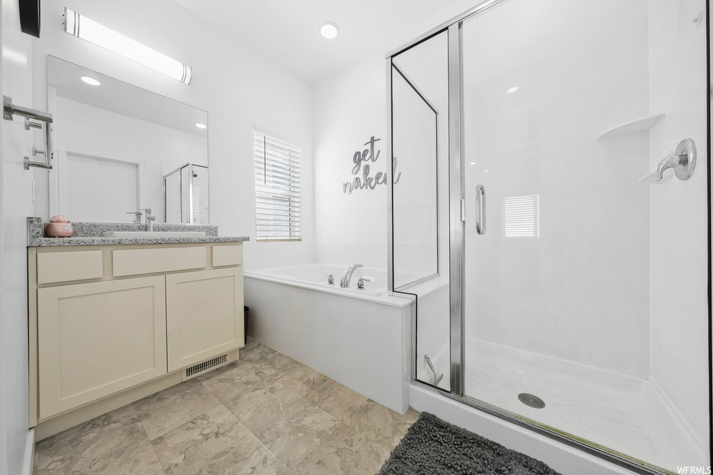 Bathroom featuring light tile flooring, separate shower and tub, mirror, and vanity