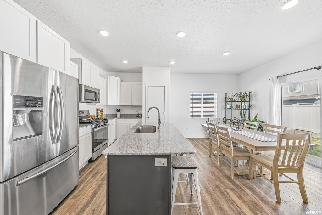 Kitchen featuring a wealth of natural light, white cabinetry, light hardwood flooring, a center island, and stainless steel appliances