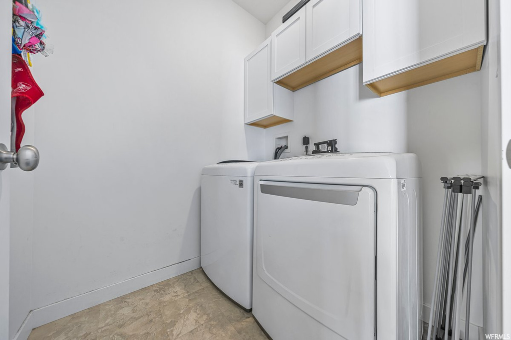 Clothes washing area with washer and dryer and light tile floors