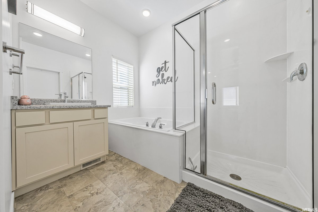 Bathroom featuring mirror, shower with separate bathtub, large vanity, and light tile floors