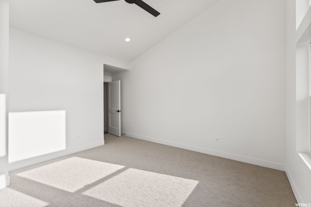 Unfurnished room featuring lofted ceiling, ceiling fan, and light colored carpet