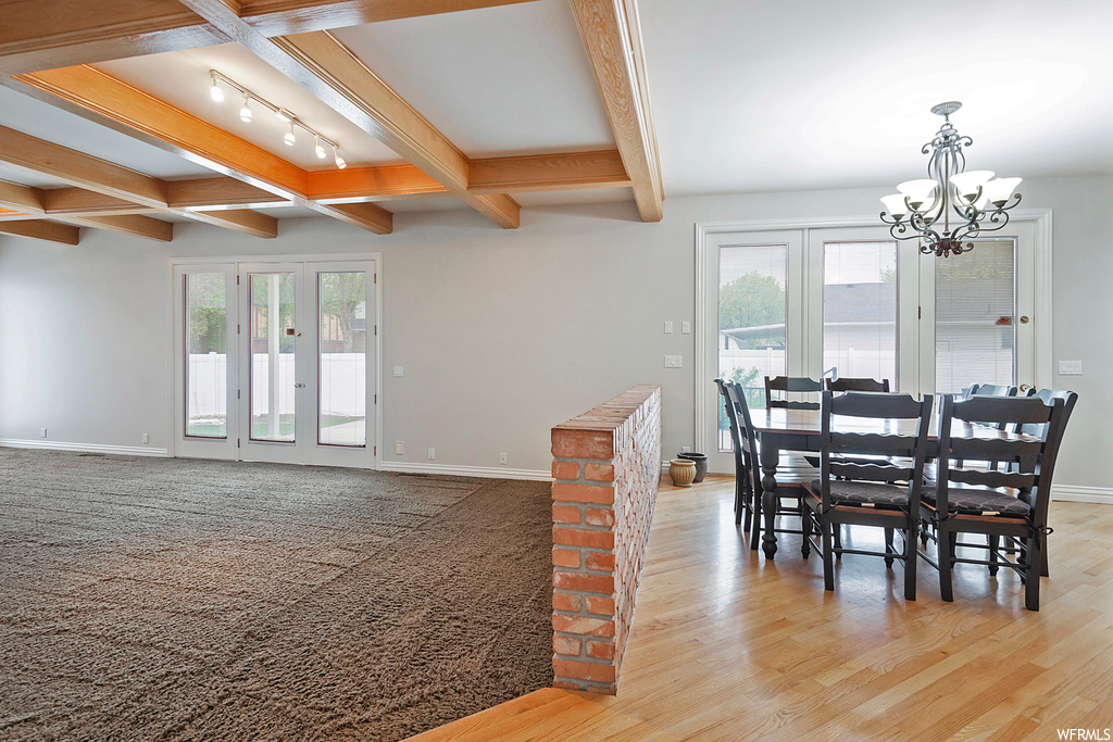 Hardwood floored dining space with beam ceiling, rail lighting, and coffered ceiling