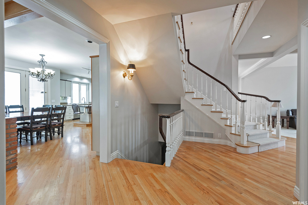 Stairs featuring a chandelier and light hardwood floors