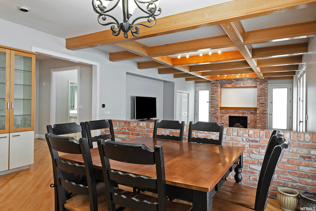 Wood floored dining area featuring brick wall, coffered ceiling, and beamed ceiling