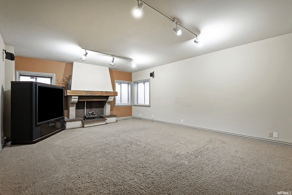 Carpeted living room featuring rail lighting, plenty of natural light, and a fireplace