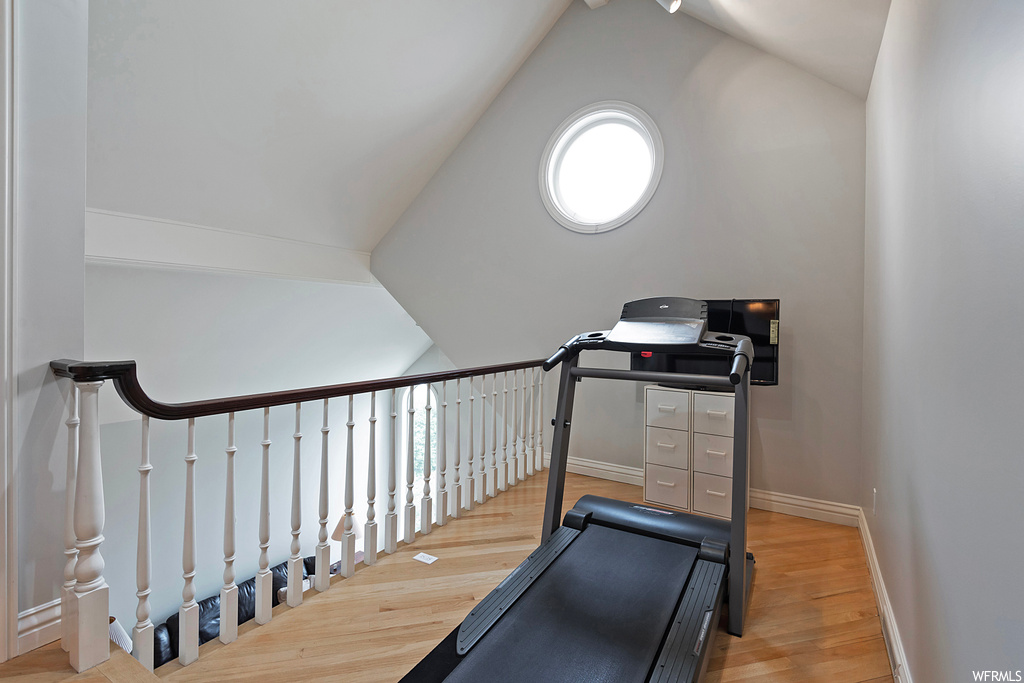 Exercise room featuring light hardwood flooring and vaulted ceiling
