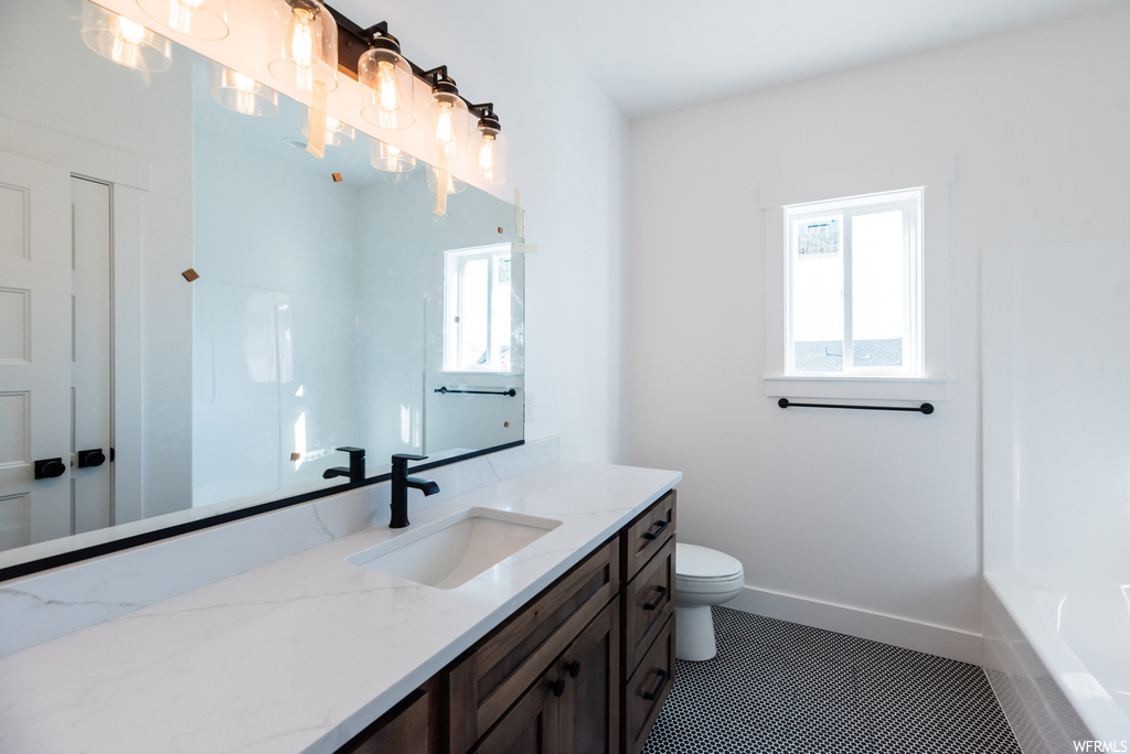 Full bathroom featuring dark tile floors, shower / bathtub combination, mirror, and vanity