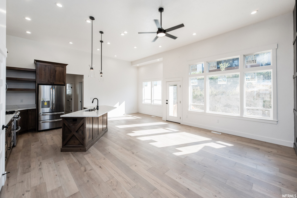Kitchen featuring hanging light fixtures, dark brown cabinets, light hardwood flooring, ceiling fan, and stainless steel fridge with ice dispenser