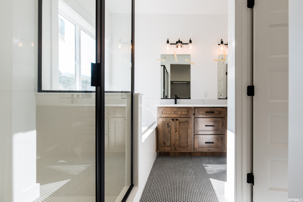 Bathroom featuring vanity, tile flooring, mirror, and a shower with shower door