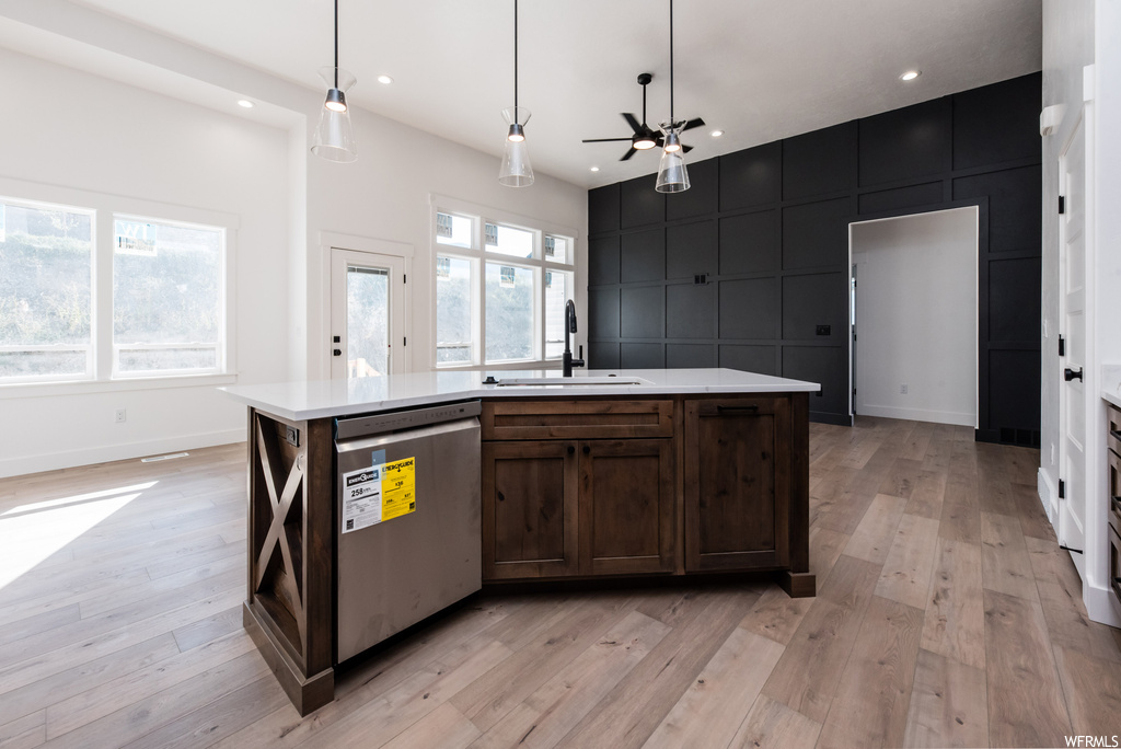 Kitchen featuring stainless steel dishwasher, light countertops, light hardwood flooring, dark brown cabinetry, and ceiling fan