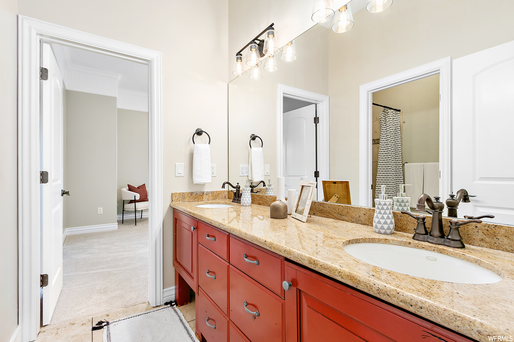 Bathroom featuring ornamental molding, mirror, and dual bowl vanity