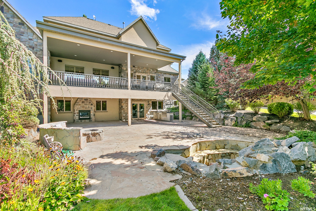 Back of property with an outdoor firepit, balcony, and a patio area