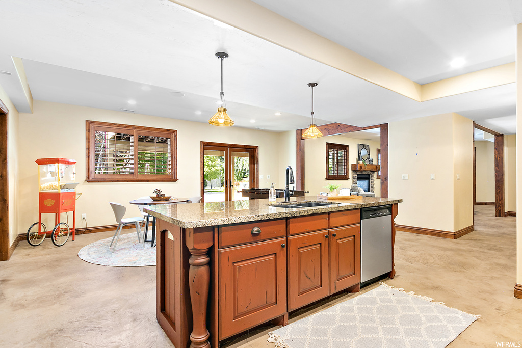 Kitchen with stainless steel dishwasher, stone countertops, decorative light fixtures, and brown cabinets