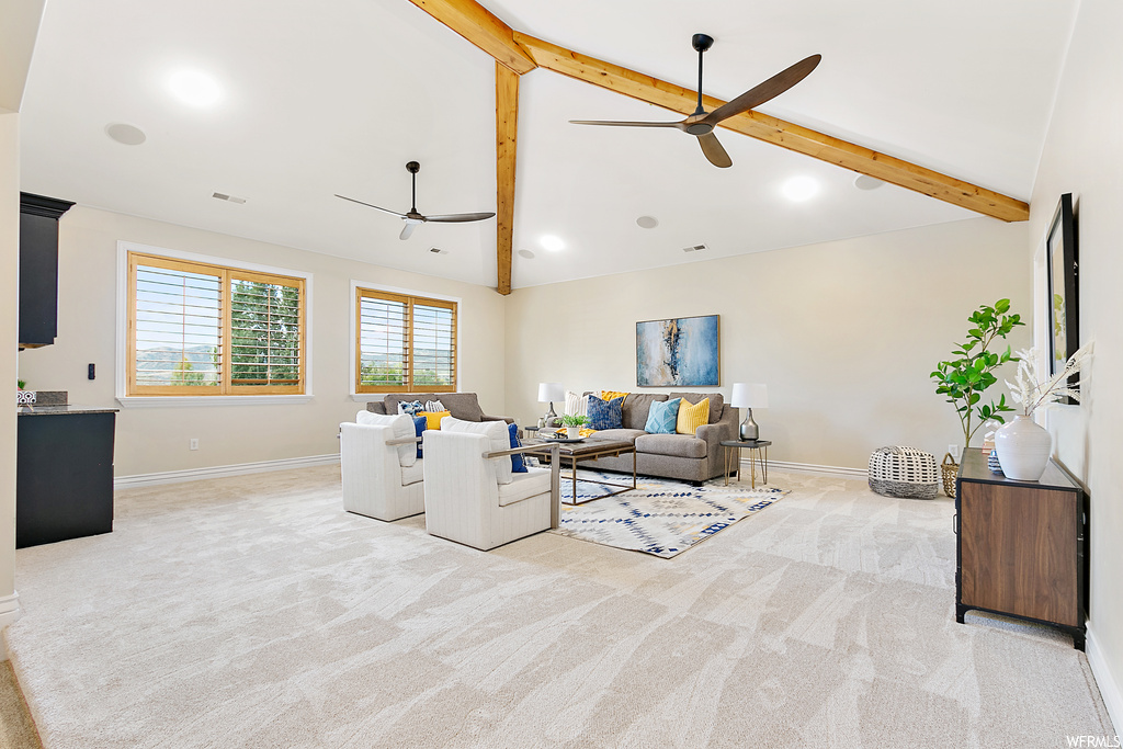 Carpeted living room featuring washer and clothes dryer, lofted ceiling with beams, and ceiling fan
