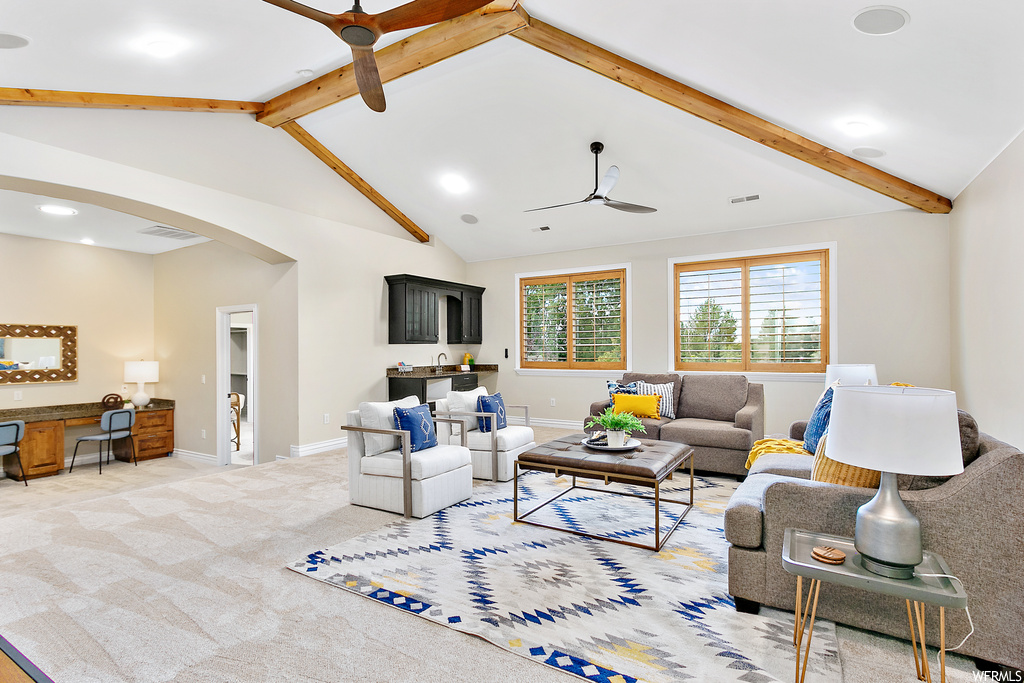 Living room with vaulted ceiling with beams, light carpet, a high ceiling, and ceiling fan