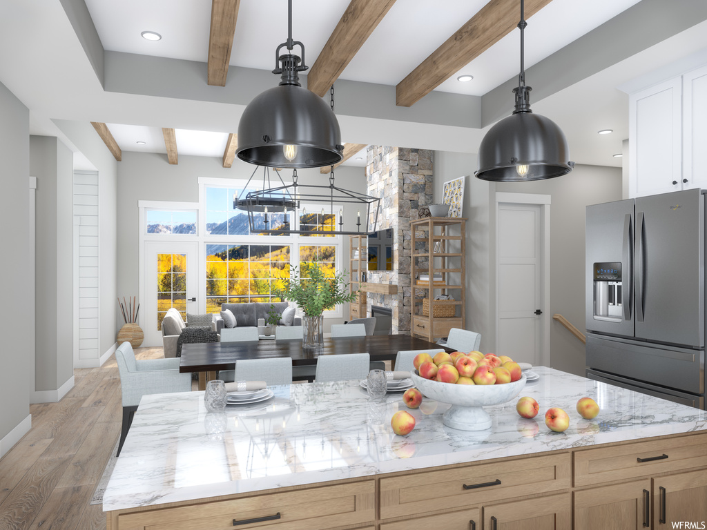 Kitchen with hanging light fixtures, beamed ceiling, wood-type flooring, light stone countertops, and stainless steel fridge with ice dispenser