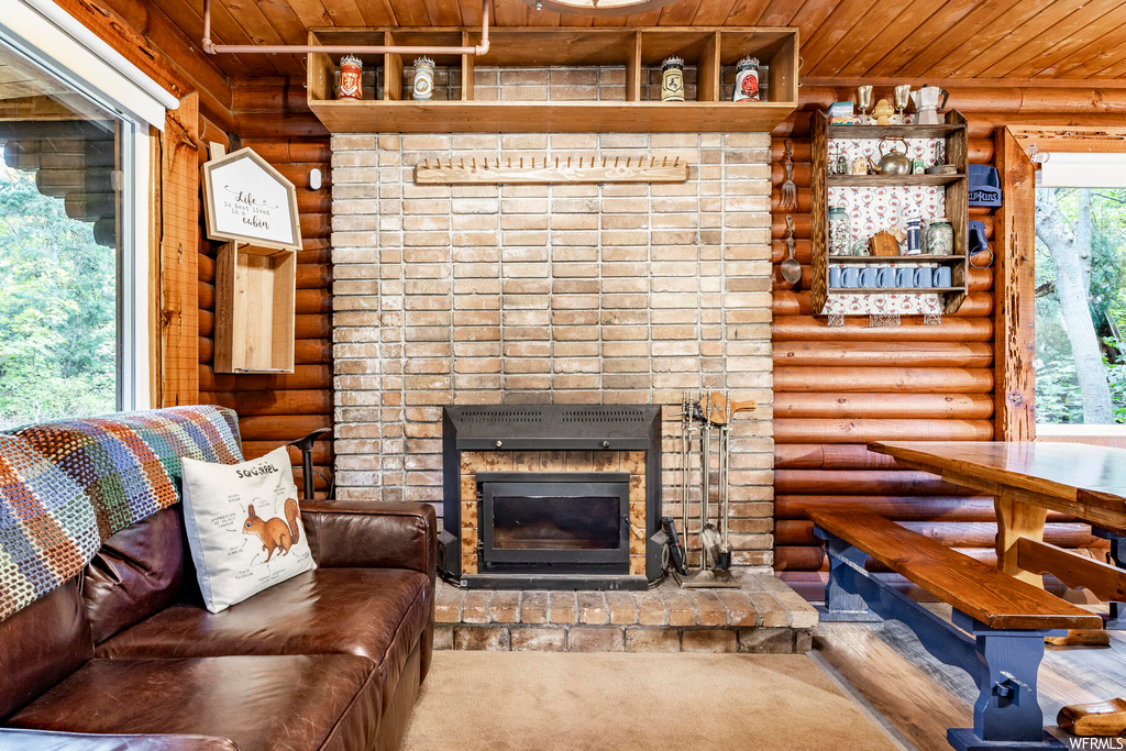 Living room with wood ceiling, log walls, and a fireplace