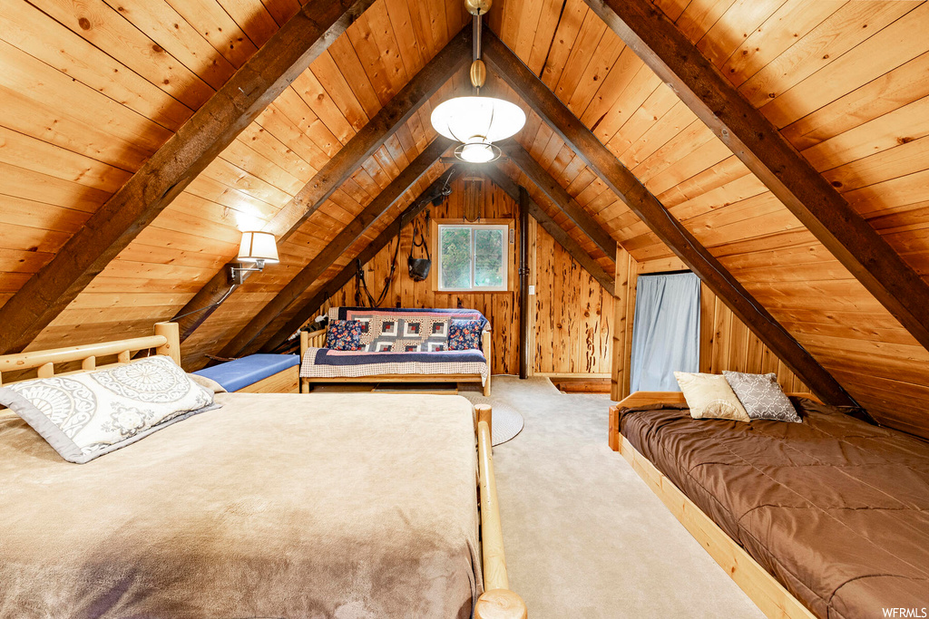 Bedroom with wooden walls, lofted ceiling with beams, wooden ceiling, and light carpet