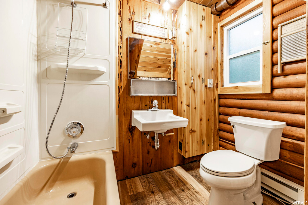 Bathroom with a baseboard radiator, log walls, light hardwood floors, wooden ceiling, sink, and wooden walls