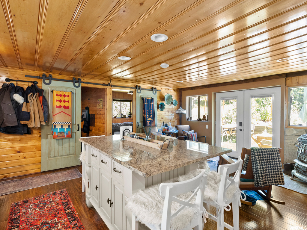 Kitchen with wood walls, hardwood flooring, wooden ceiling, and a kitchen island