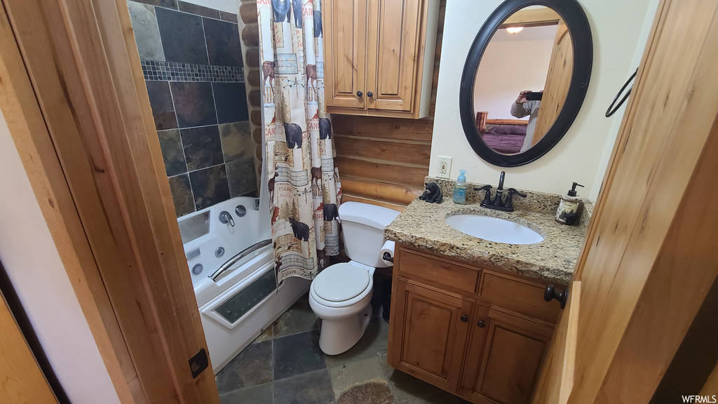 Full bathroom with shower / tub combo, large vanity, dark tile flooring, and mirror