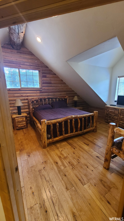 Hardwood floored bedroom with multiple windows and vaulted ceiling