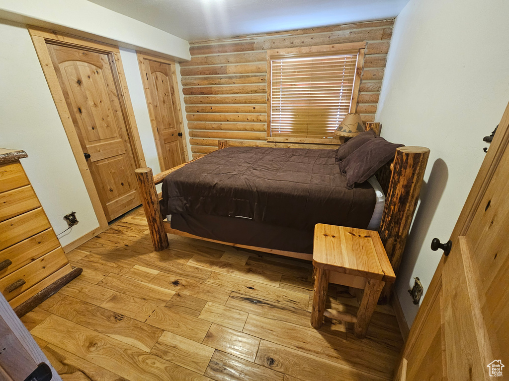 Bedroom with light wood-type flooring and rustic walls