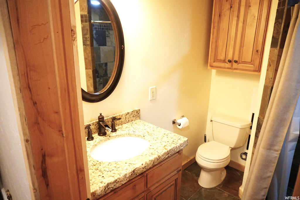 Bathroom featuring dark tile floors, oversized vanity, and mirror