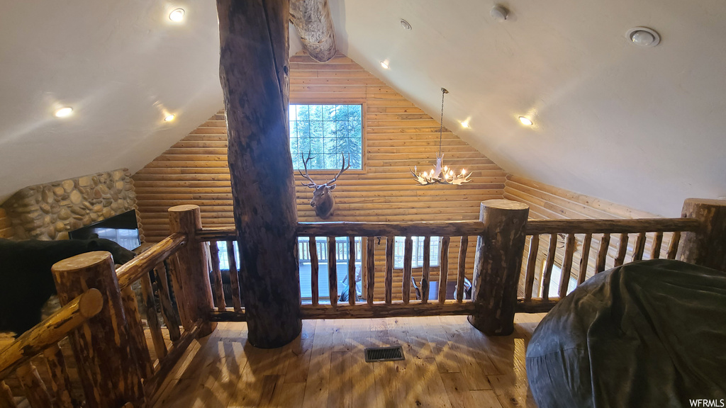 Interior space featuring dark hardwood floors, vaulted ceiling, and log walls
