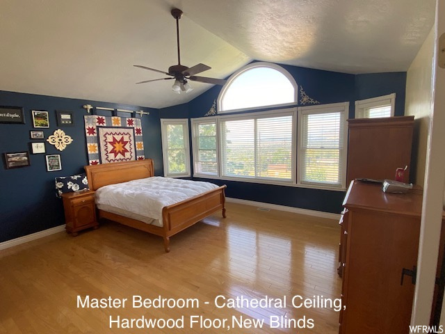 Hardwood floored bedroom featuring ceiling fan and lofted ceiling