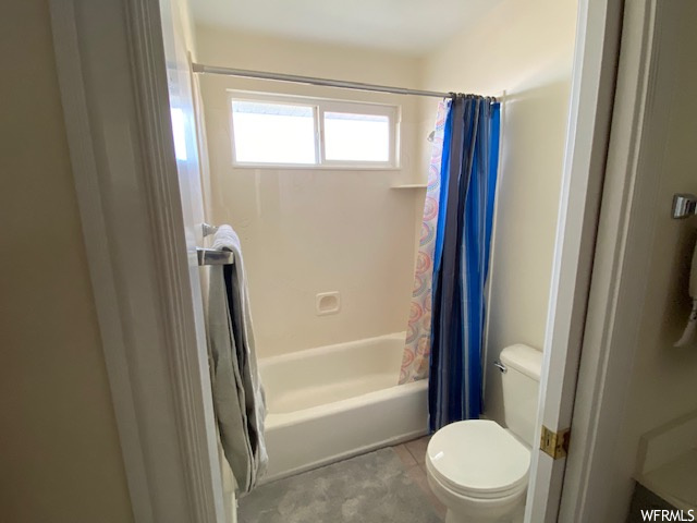 Bathroom with tile floors, shower / tub combo, and toilet