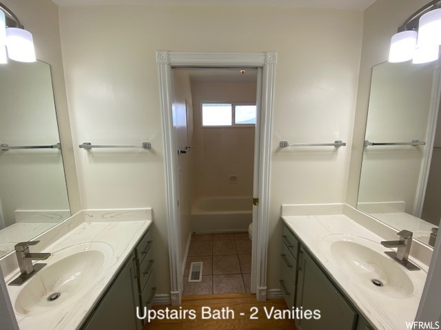 Bathroom with dark tile flooring, double large vanity, and mirror
